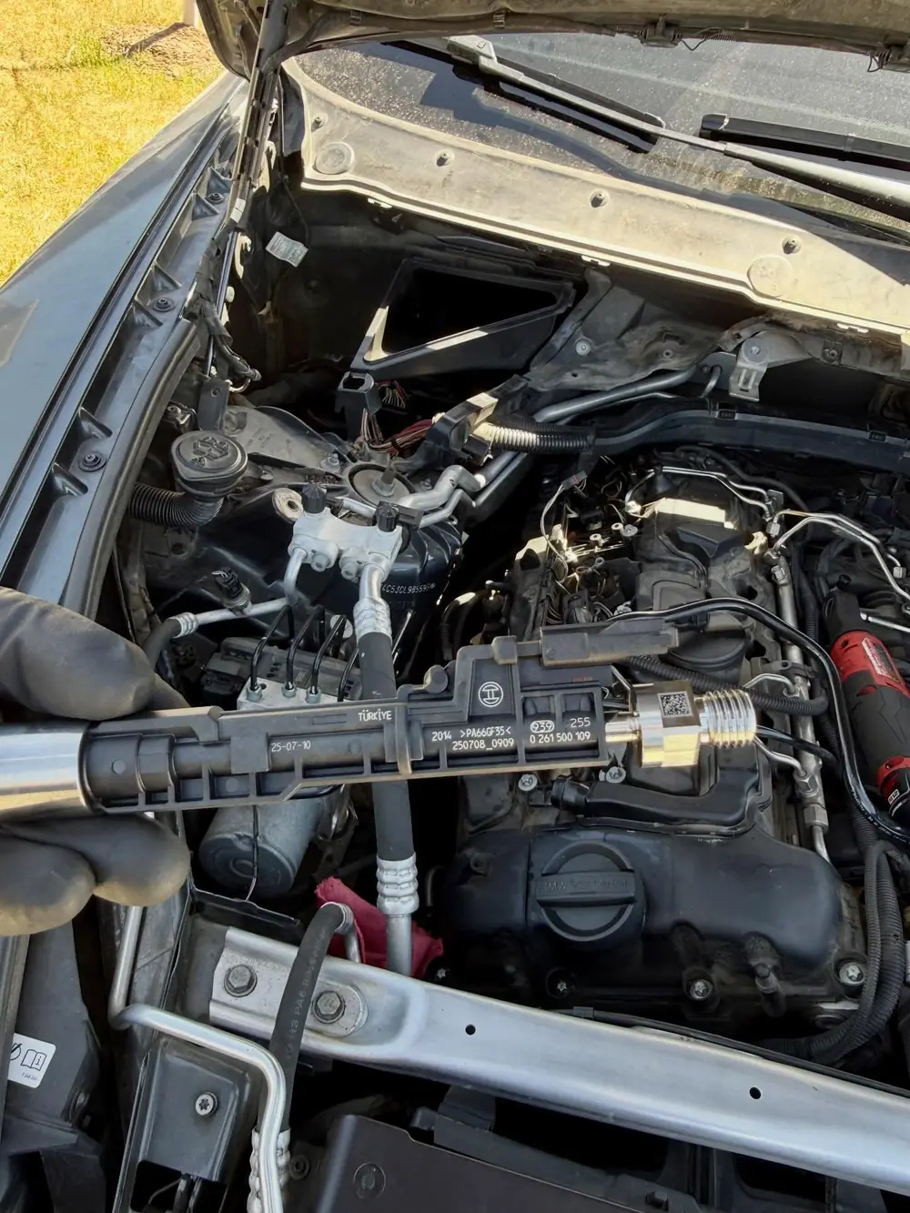 BMW fuel injector held over the engine bay