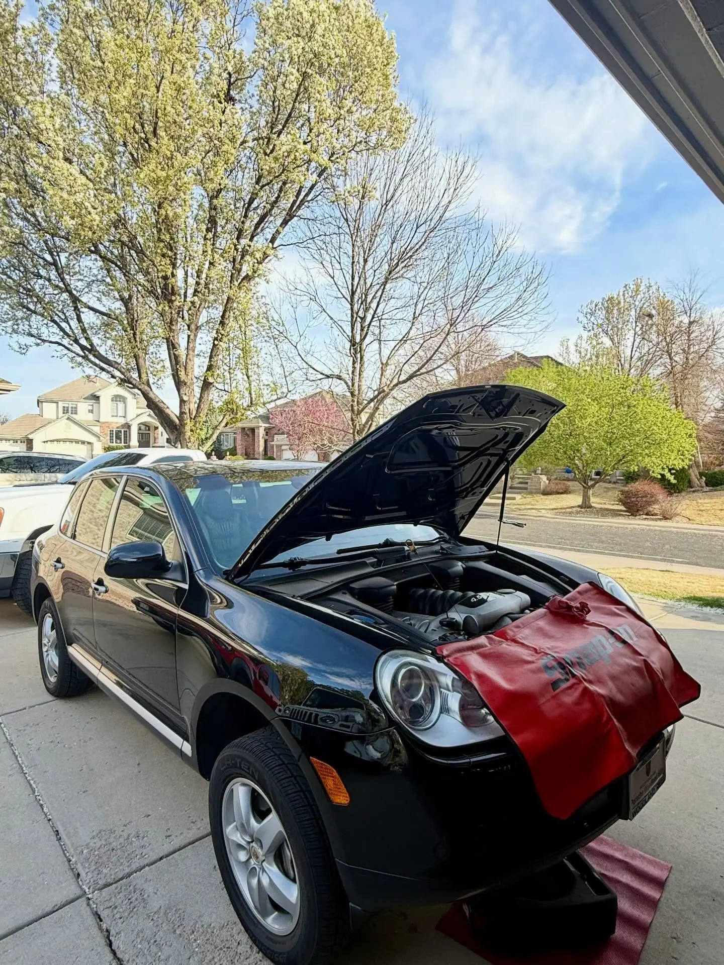 A Porsche Cayenne serviced on a suburban driveway